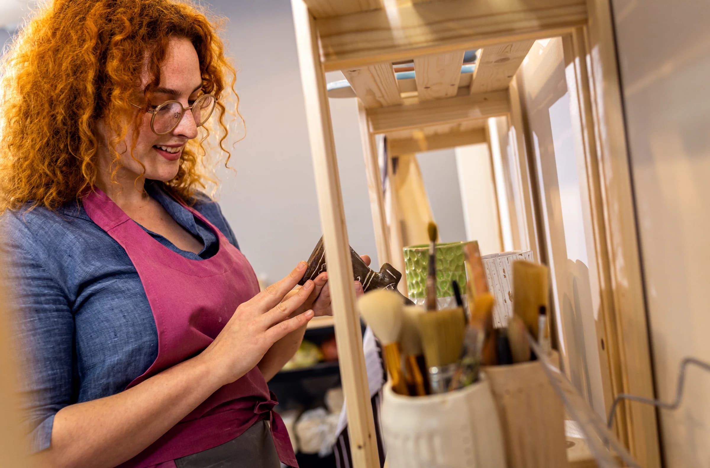 A business owner checks inventory in her pottery studio with a tablet.
